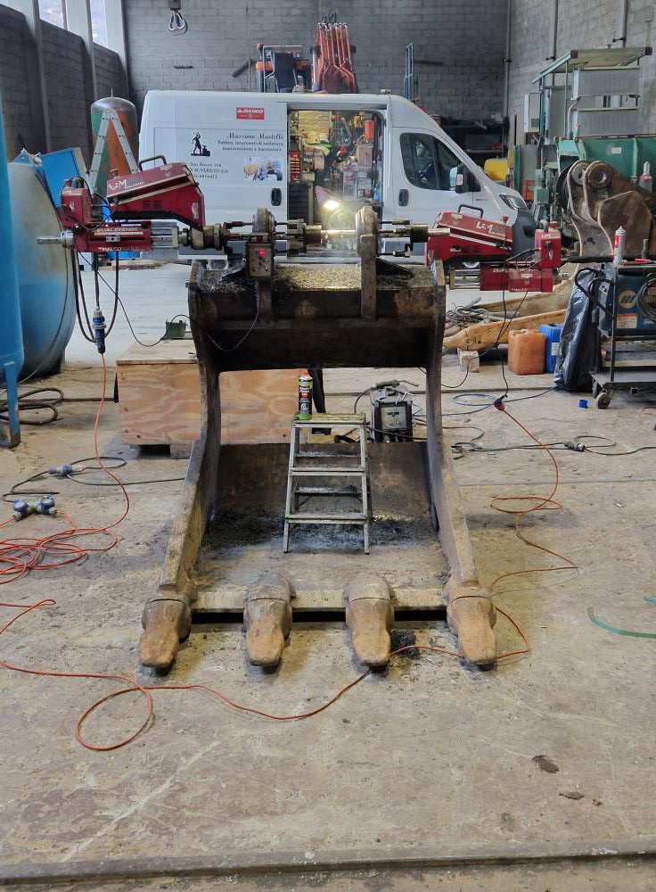 Riparazione benna escavatore sotto pressa - officina Martelli Suvereto